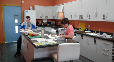 Two young people work in the brand new Life Skills Room at New Struan School