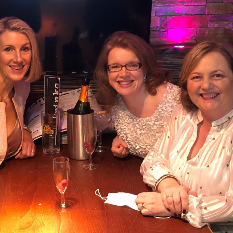 Three people sit at a table, drinks on the table