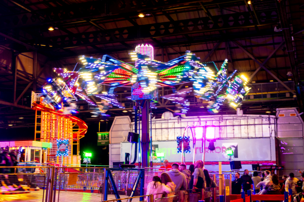 Image is of an indoor fun fair with lots of lights giving a carnival experience