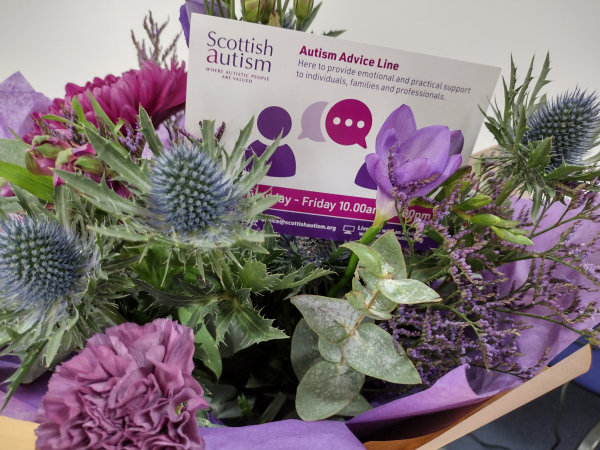 Image is of a floral bouquet, a card in the centre with information about an Autism Advice Line