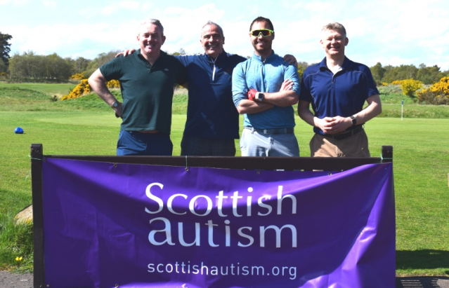 Four men after a game of golf, standing smiling behind a Scottish Autism purple banner