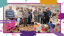 Image is of a group of people together, a staff team and people supported at Scottish Autism's service Art Opportunities, everyone smiles for the camera