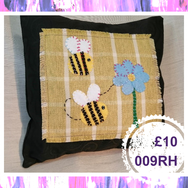 A small square cushion with two bees and a flower and bee, £10, 009RH