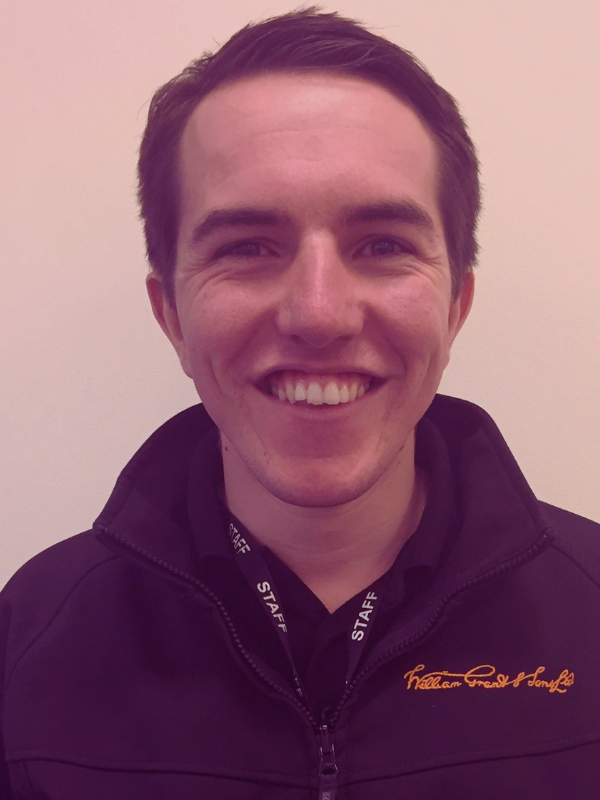 A young man in a black fleece smiles to the camera