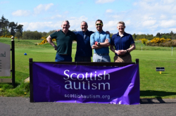 Four golfers smile for the camera while standing behind a purple Scottish Autism banner
