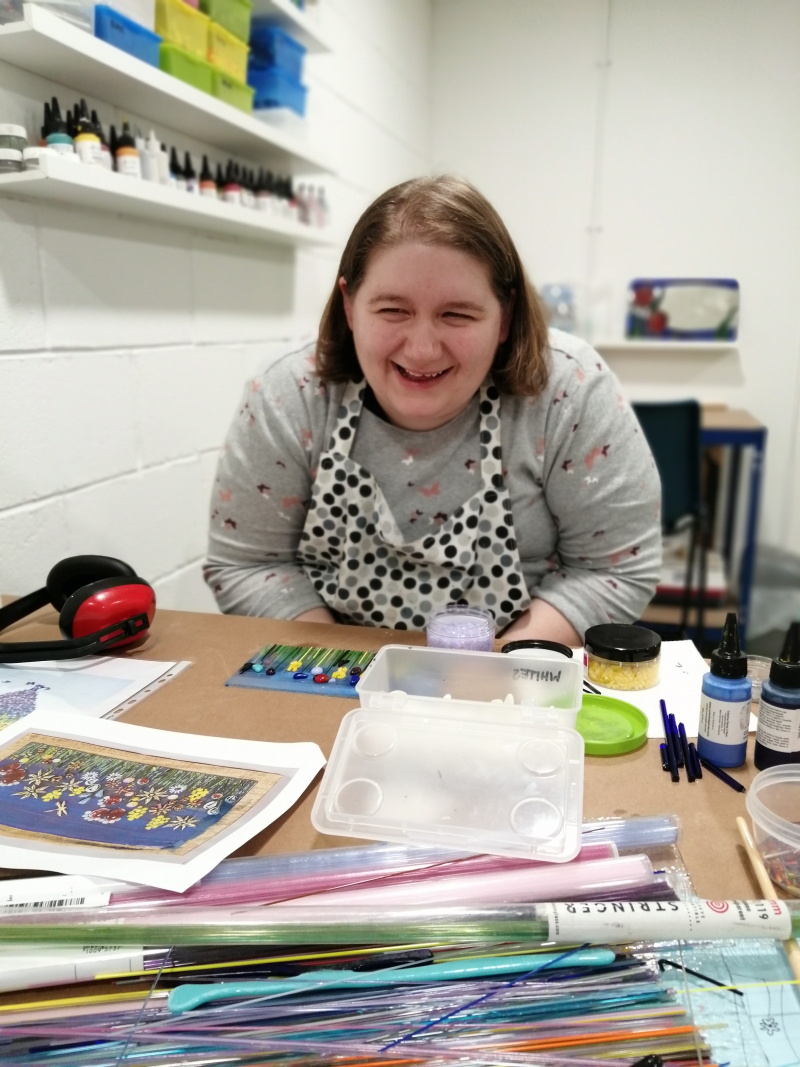 Person laughs while creating an artwork, studio environment, art supplies