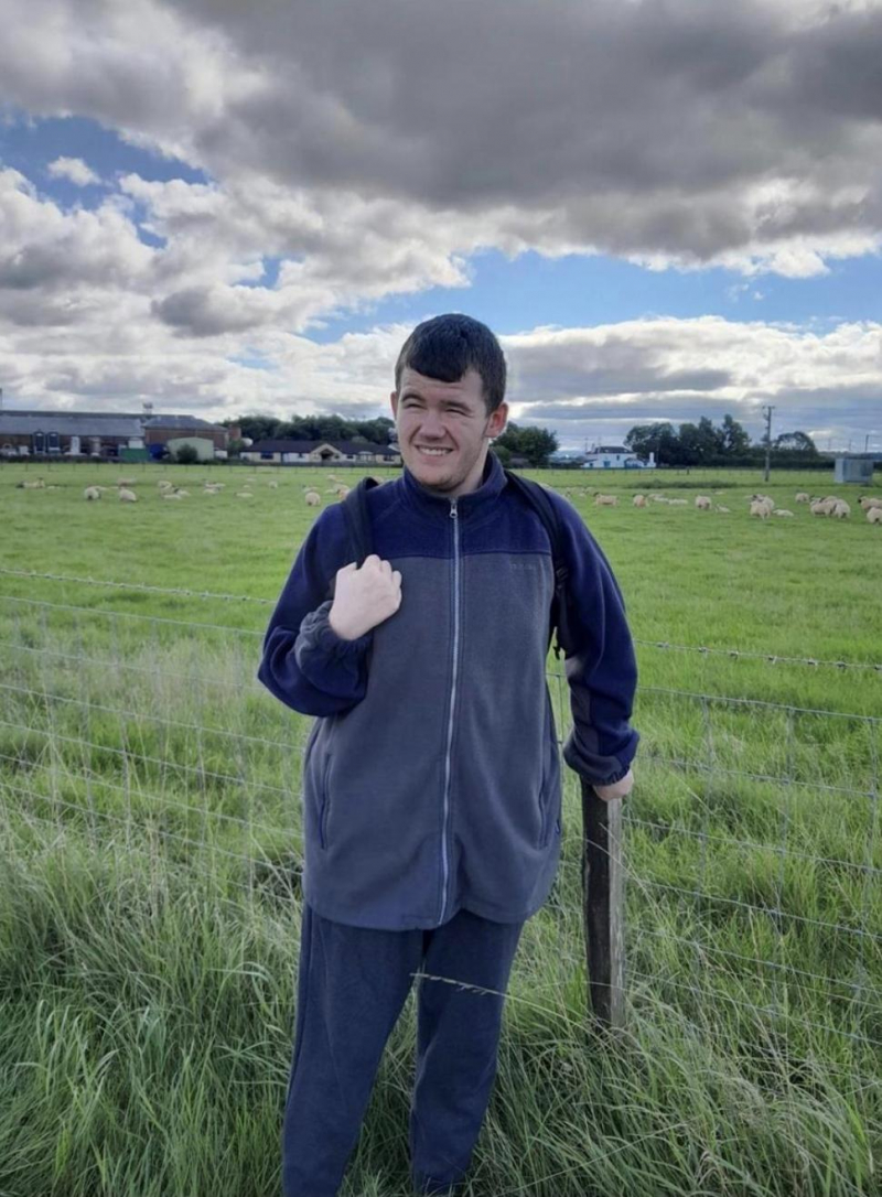 Young adult standing in a field, smiling