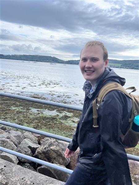 Person walking outdoors and smiling with water landscape in background