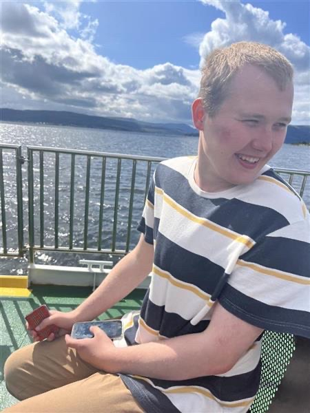 Boy smiling outdoors with sea in background