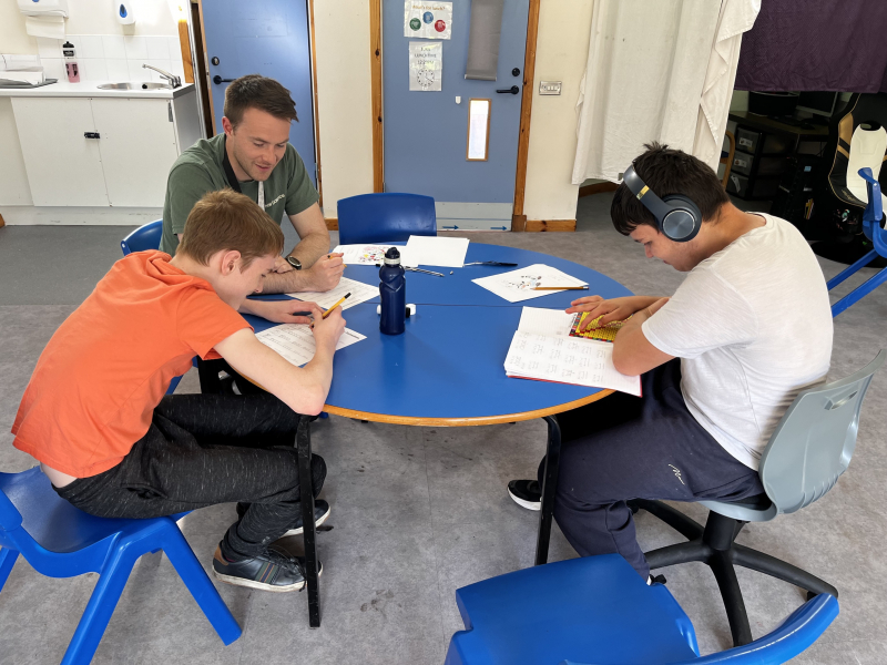 adult and two children sitting round a table working together