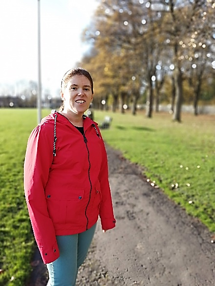 A young woman smiles to the camera while on a path in the countryside