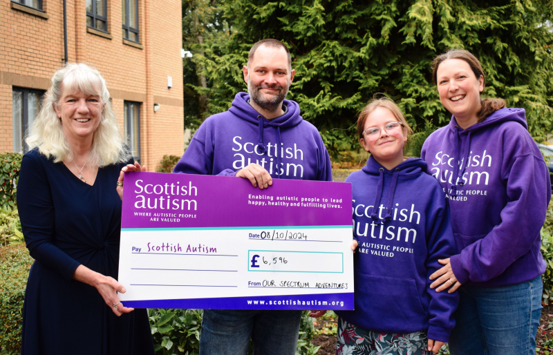 Image is of Dorry McLaughlin, CEO of Scottish Autism, receiving a cheque from Ian, Eve and Sarah Alderman