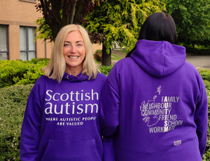 Image is of two people wearing purple hoodies, outdoors