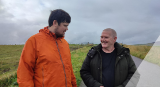 Image is of two people on a walk in a remote location, talking to each other