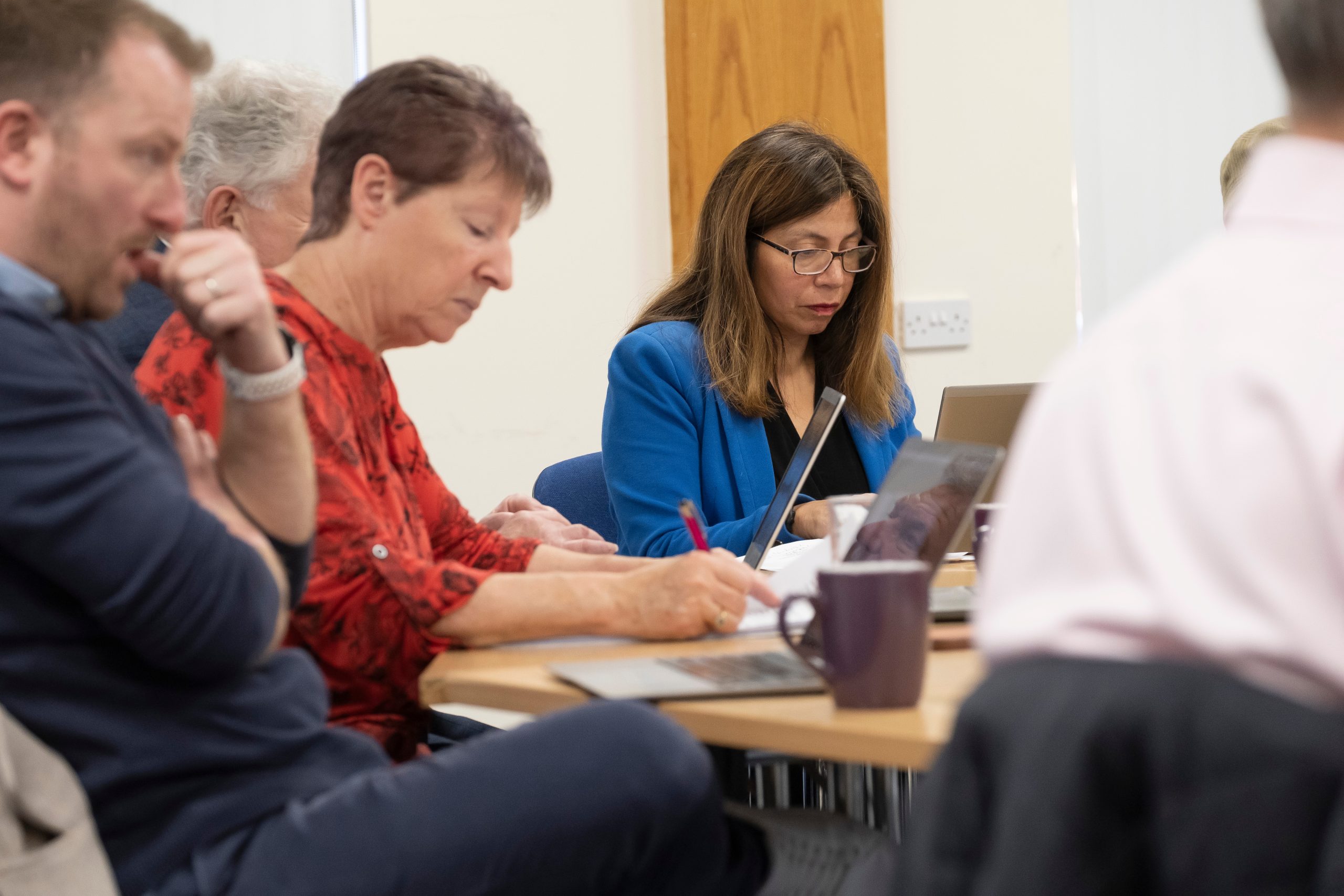 3 people sitting thinking and working at a desk