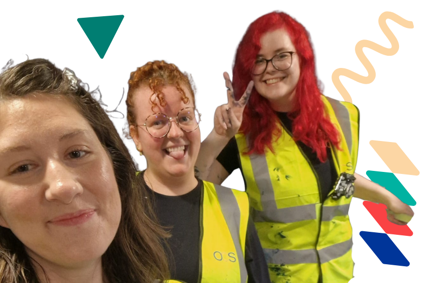 Three people in high visibility vests pose for the camera and smile