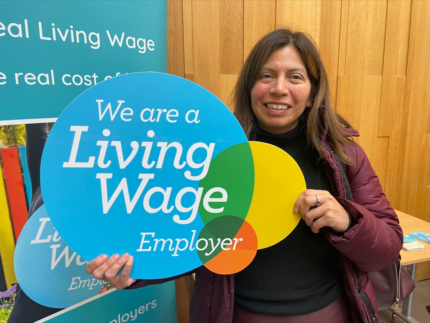 Female holding a sign 'We are a Living Wage Employer' sign