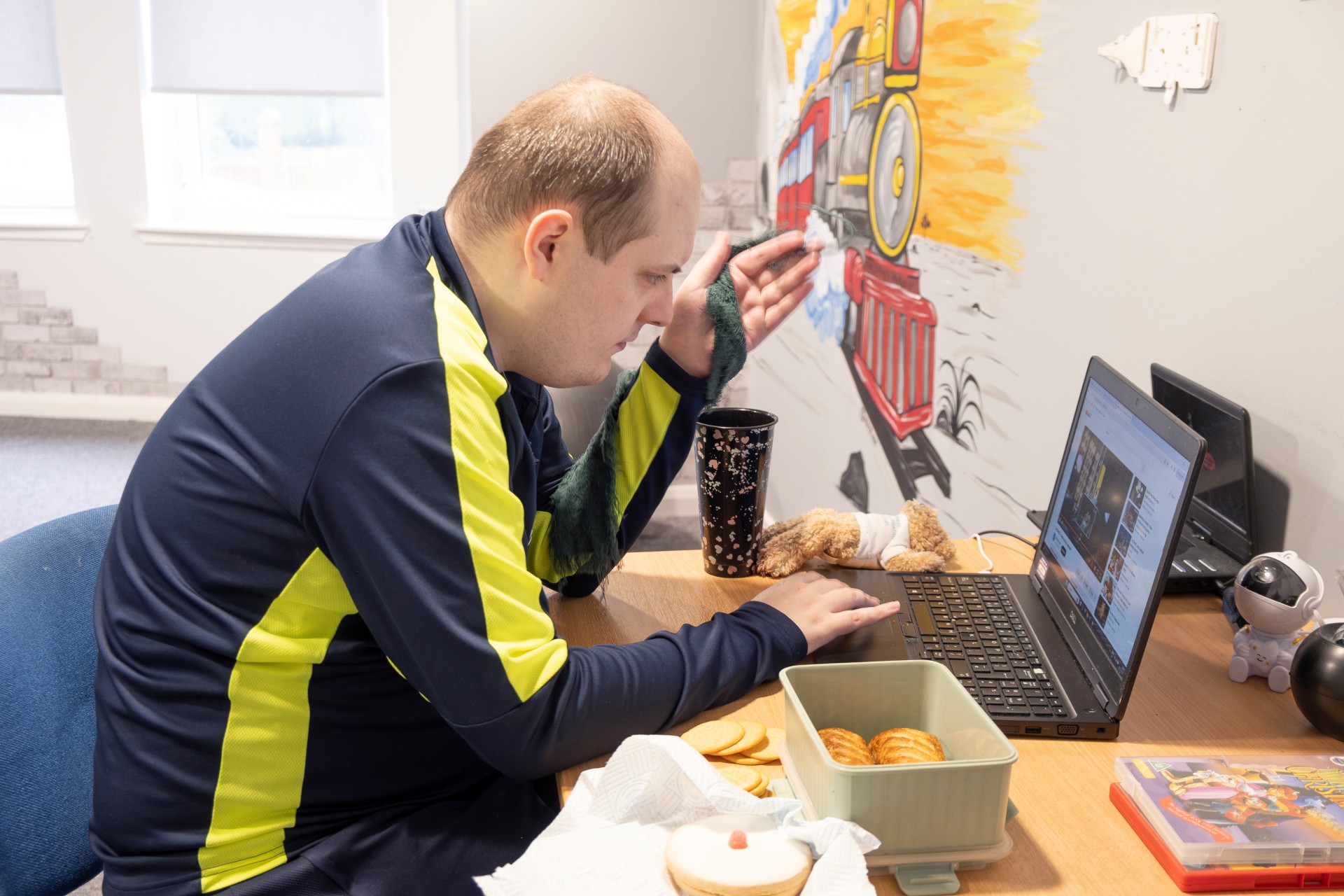 Image is of someone working on a computer and eating their packed lunch