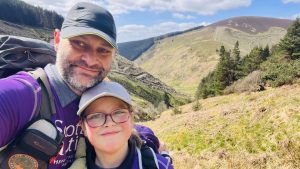 Two Scottish Autism supporters (a father and daughter) smile for the camera with a mountain landscape behind them.