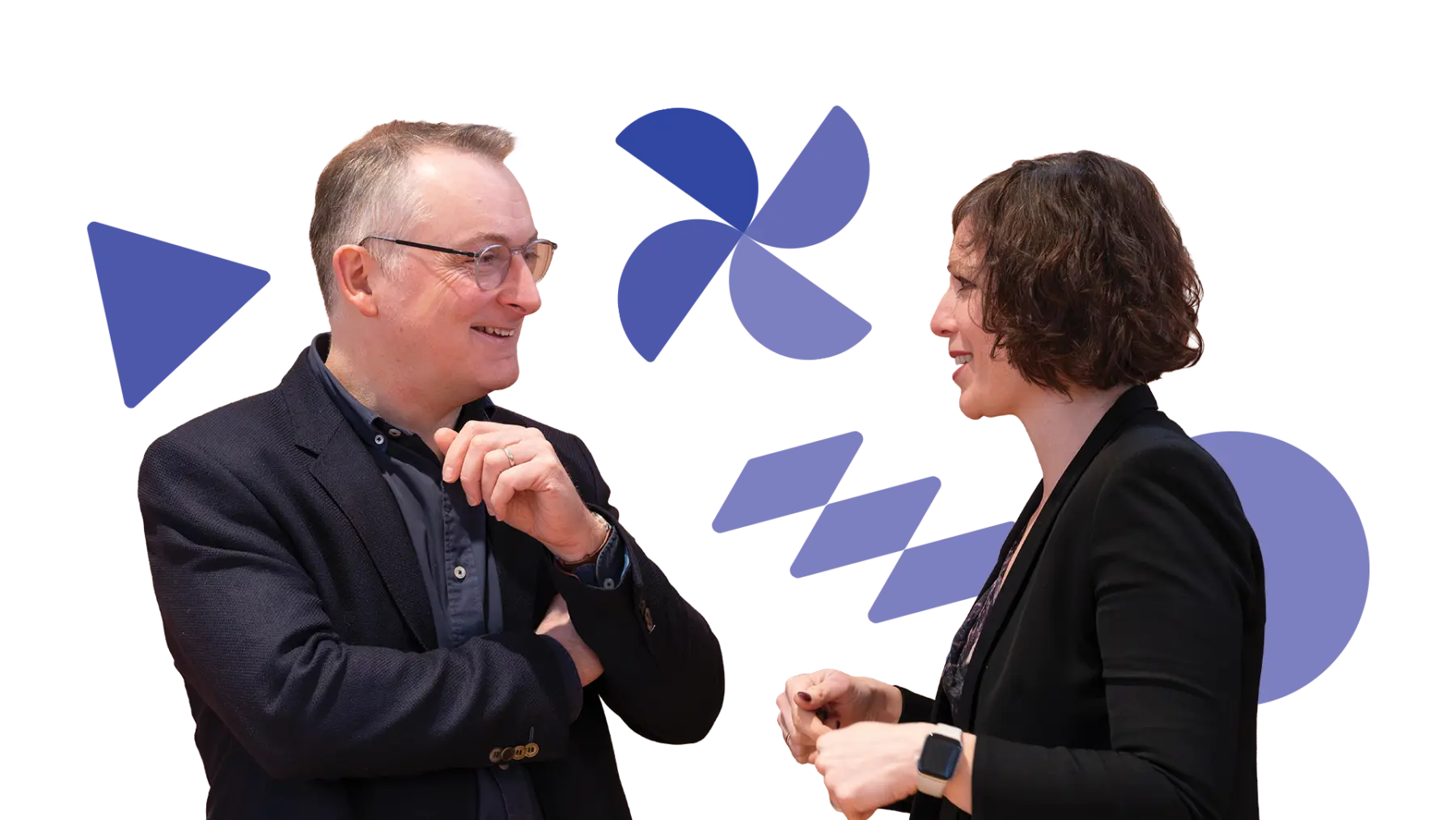 Image is of two people wearing suits, smiling and talking together