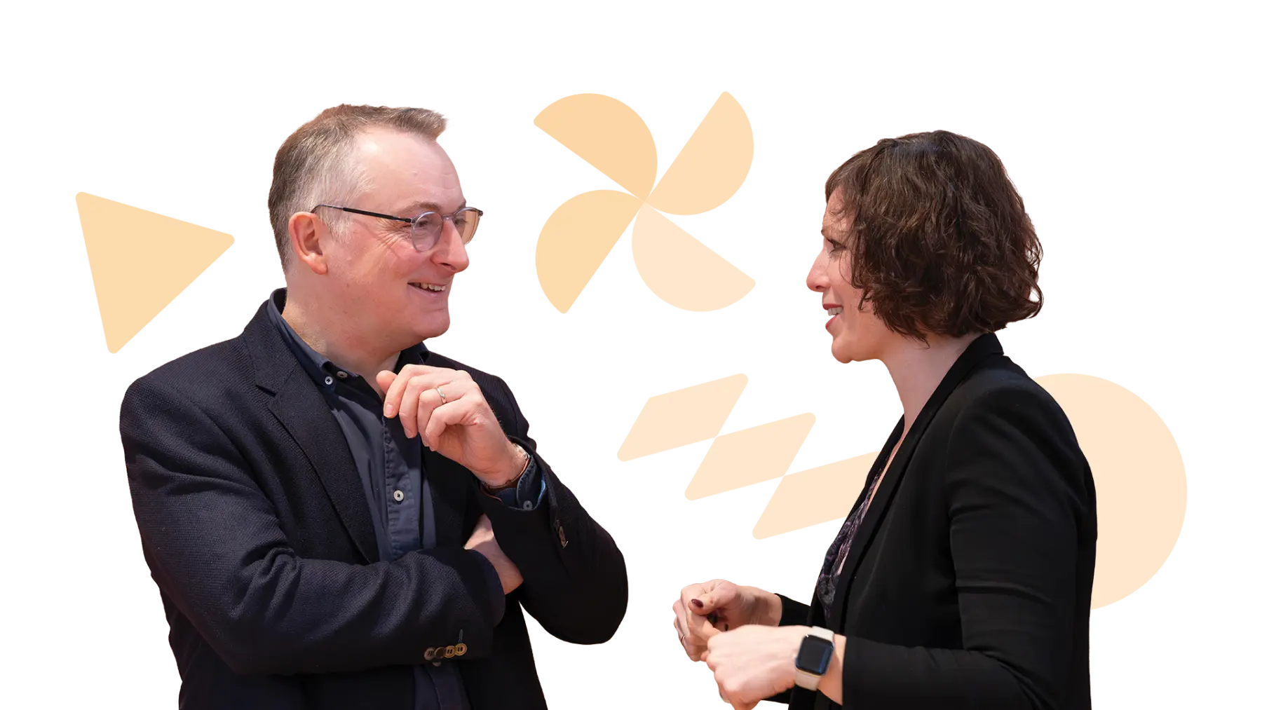 Image is of two people wearing suits, smiling and talking together