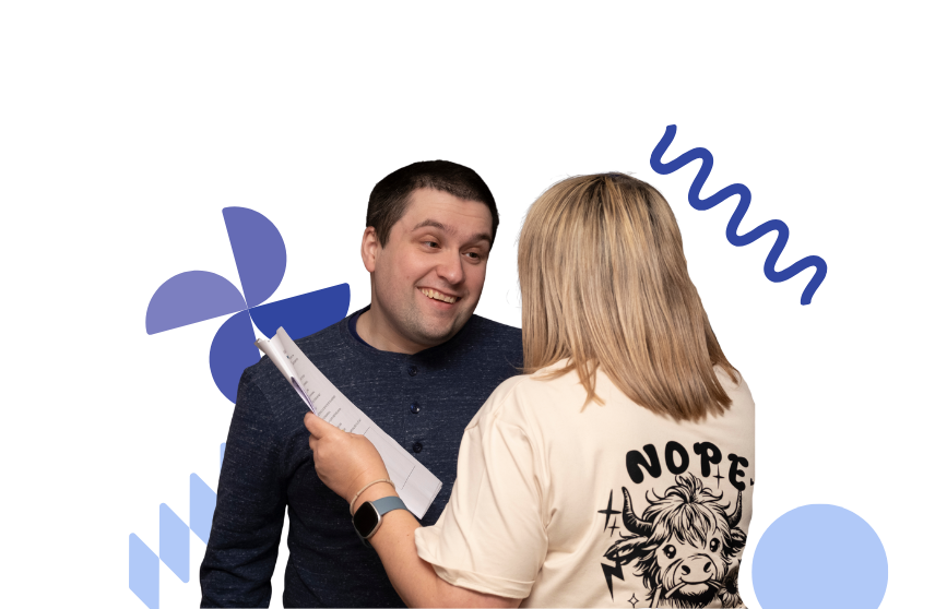 Image is of two people at a musical theatre group together with a script in hands, the person with dark hair is smiling to the other