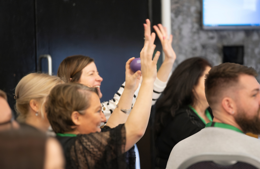 People smiling and happy with their hands in the air doing an inclusive applause