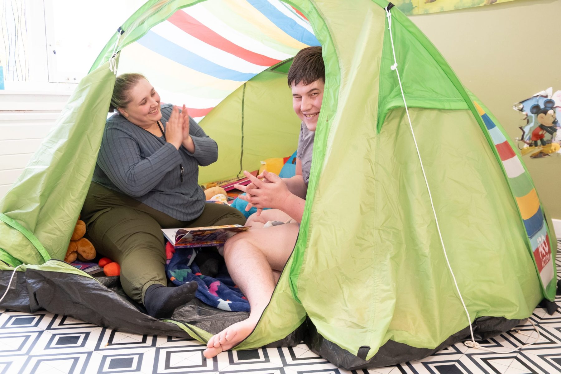 Two people clapping and smiling inside a tent