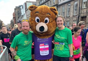 Image is of two runners with Scottish Autism's mascot Wallace the Bear at a running event