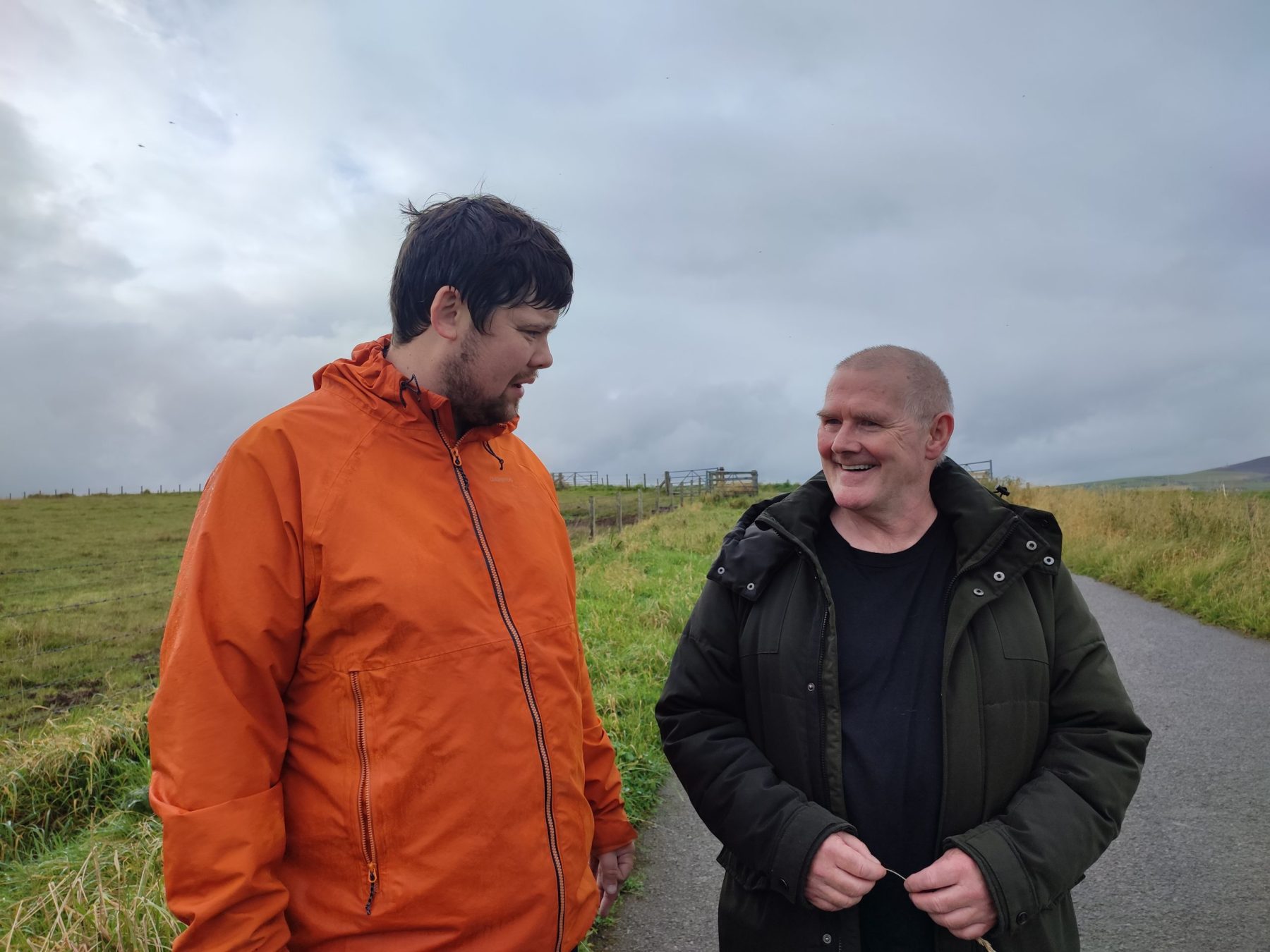 Two men smiling together, outside