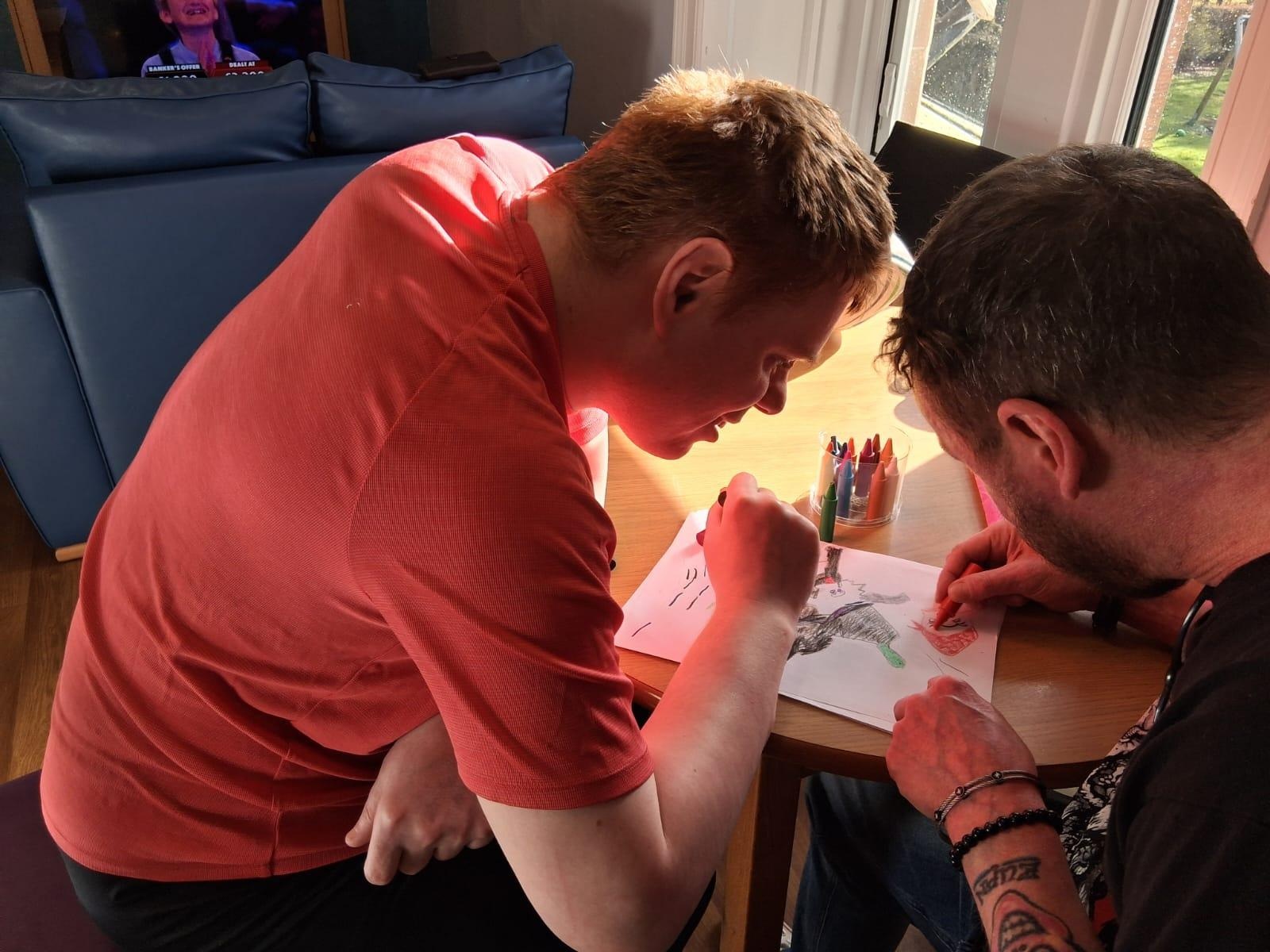 Two people sat at a table drawing a picture