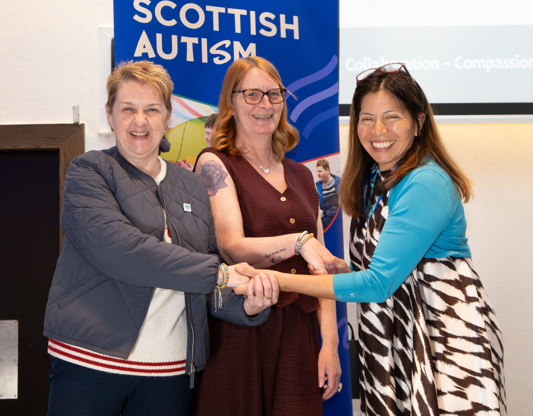 Three women smiling and shaking hands