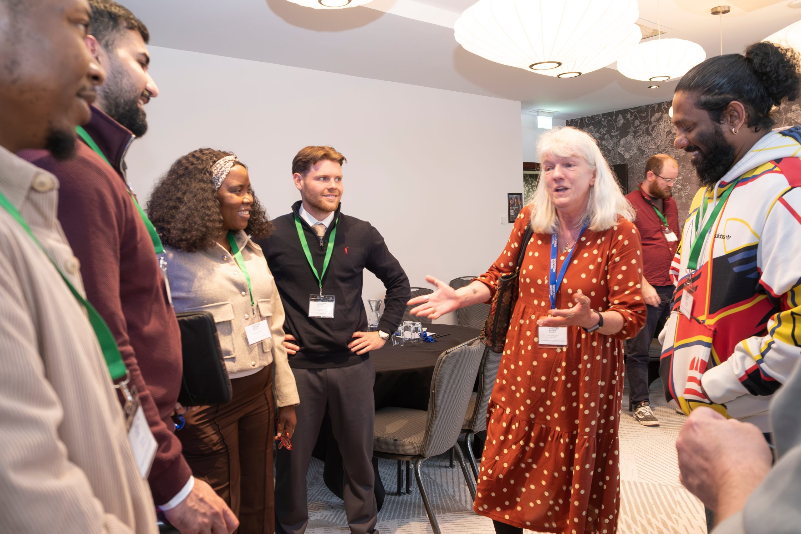 A group of people standing talking and smiling