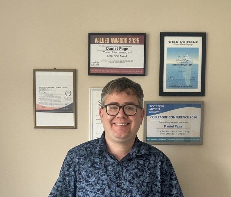 Daniel stood infront of the wall where all of his certificates are displayed