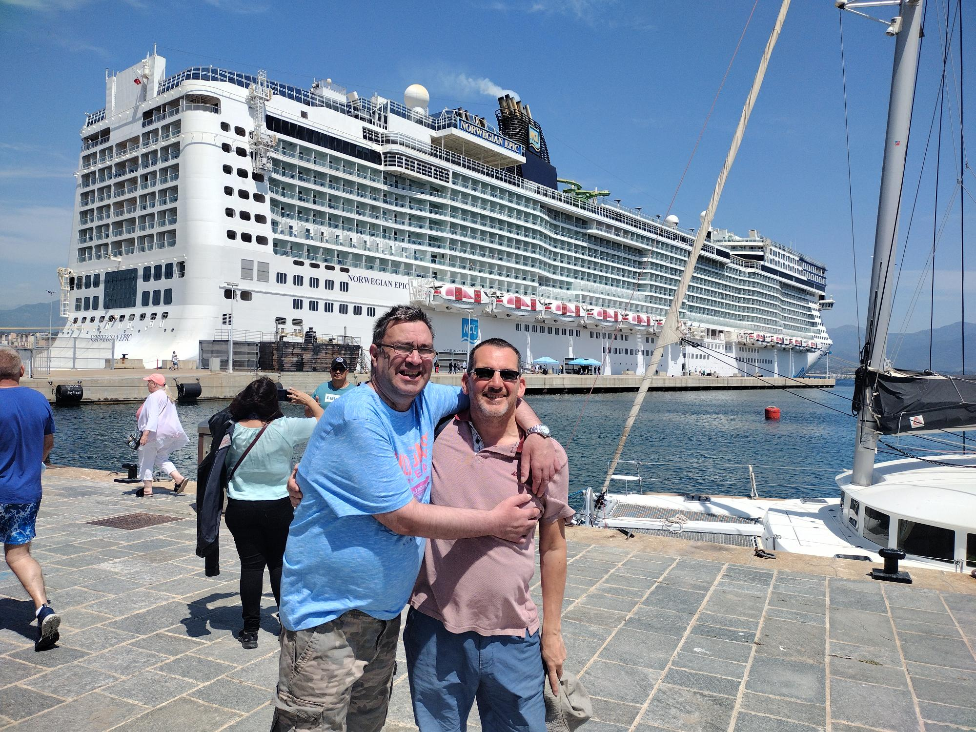 Two men stood on the dock in front of a large cruise ship in Corfu