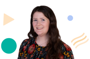 Image of Aimee Fletcher, a person with long brown hair and a colourful dress smiling for the camera